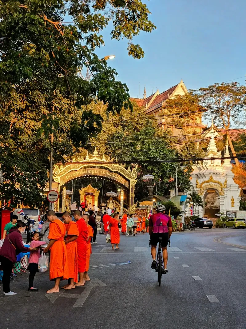 Sampath weaves through bustling Doi Suthep street as monks bless a family beside a temple