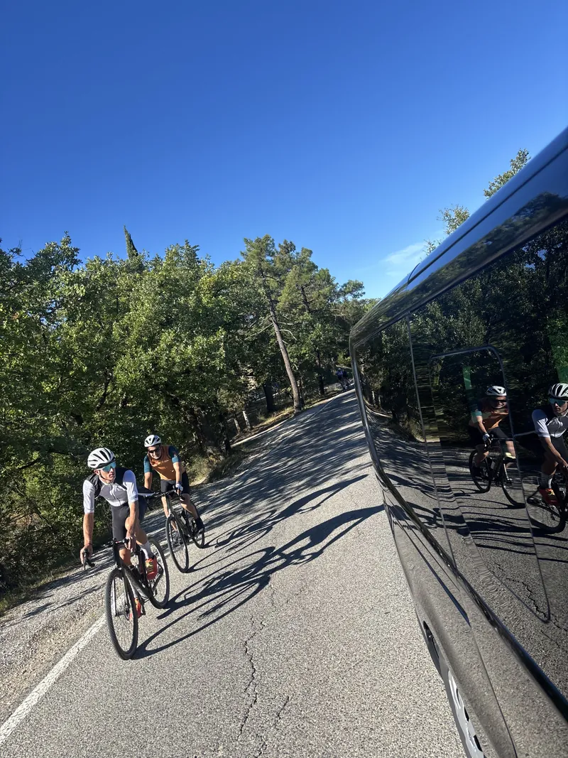 Two riders on a road, seen beside the support van