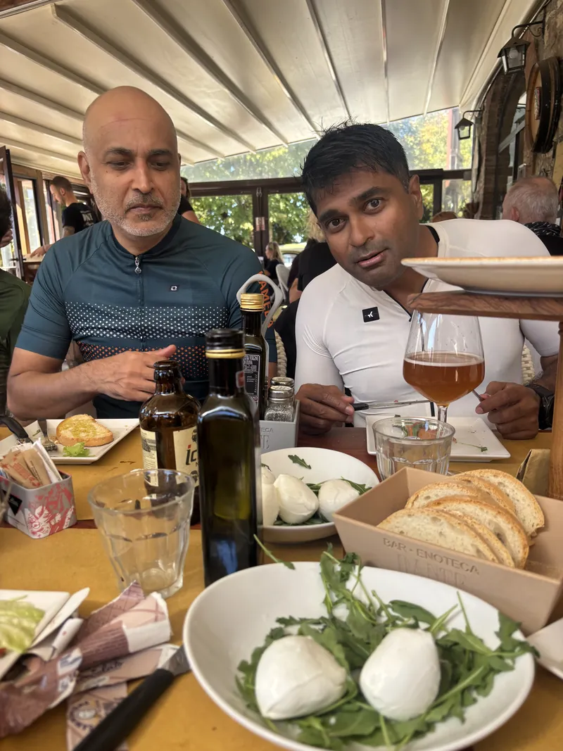 Two riders at a lunch table with balls of fresh mozzarella, bread and olive oil