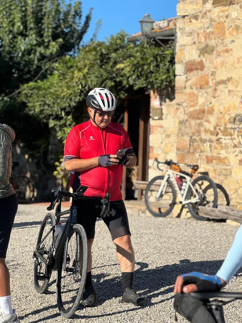 A rider in red holding his bike outside a stone building