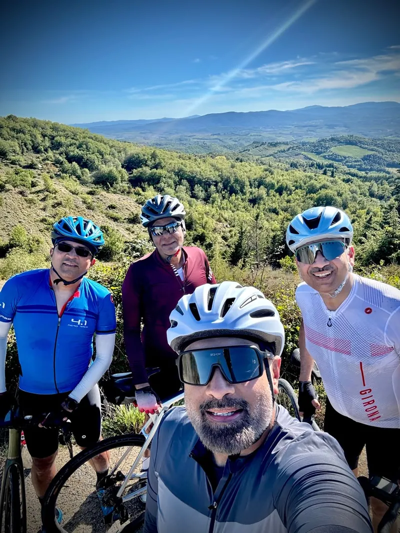 Four riders take a selfie on a hilltop, a wide green valley behind