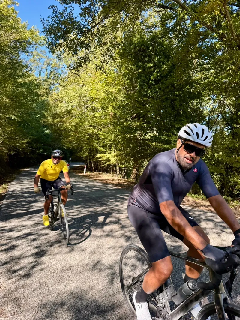 Two riders on a road through woodland