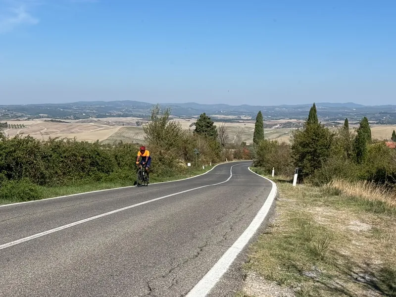 A rider on a long road through open, rolling farmland