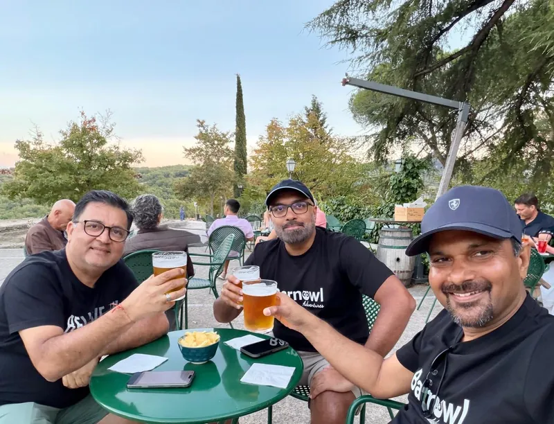 Three riders raising glasses of beer at a garden table in the evening light