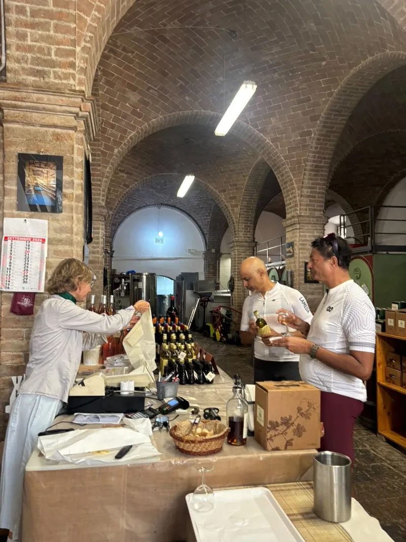 Riders at a tasting counter in a vaulted brick room, bread and bottles on the table