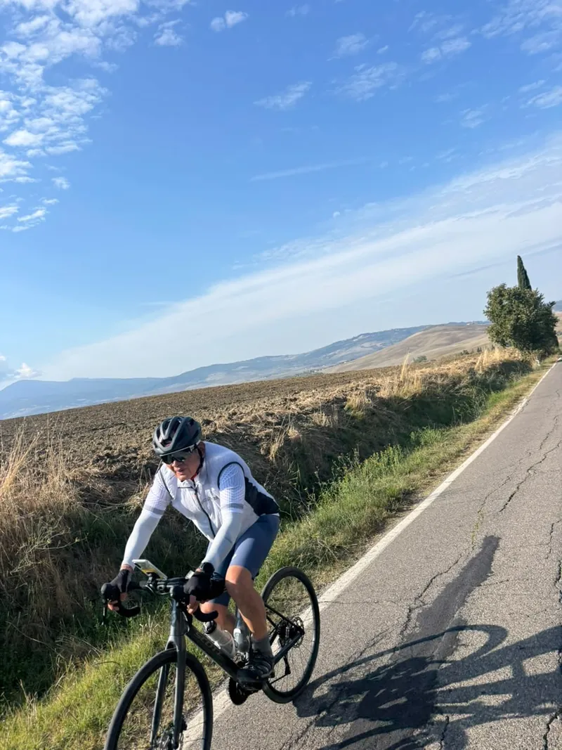 A rider on a road through bare fields, hills in the distance