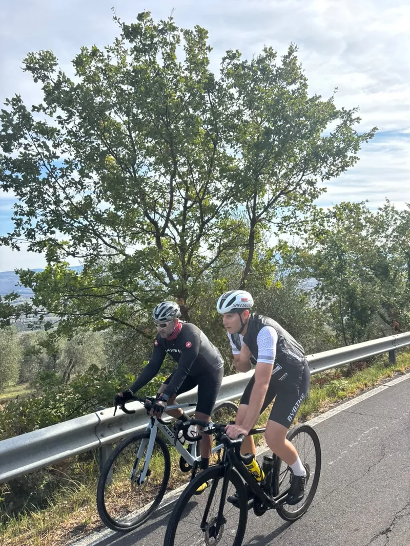 Two riders on a road above a wooded valley