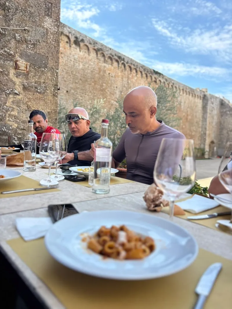 A plate of pasta on a table set against the high walls of a fortress