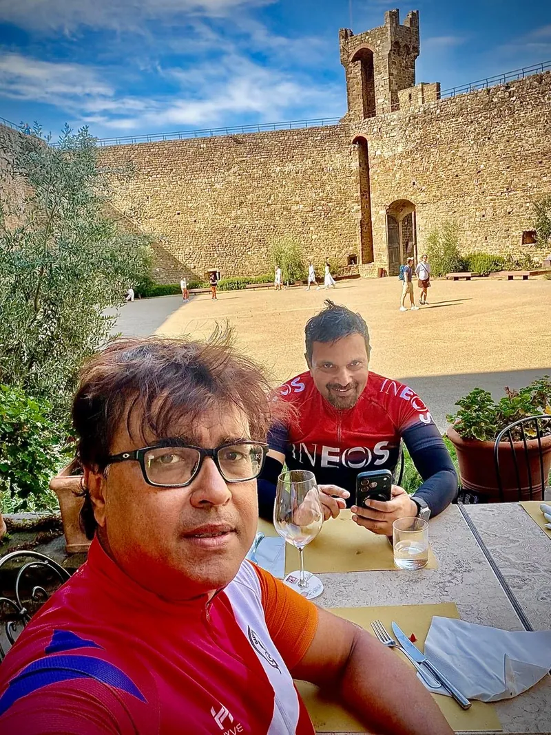 Two riders at a table in a castle courtyard, a stone tower behind