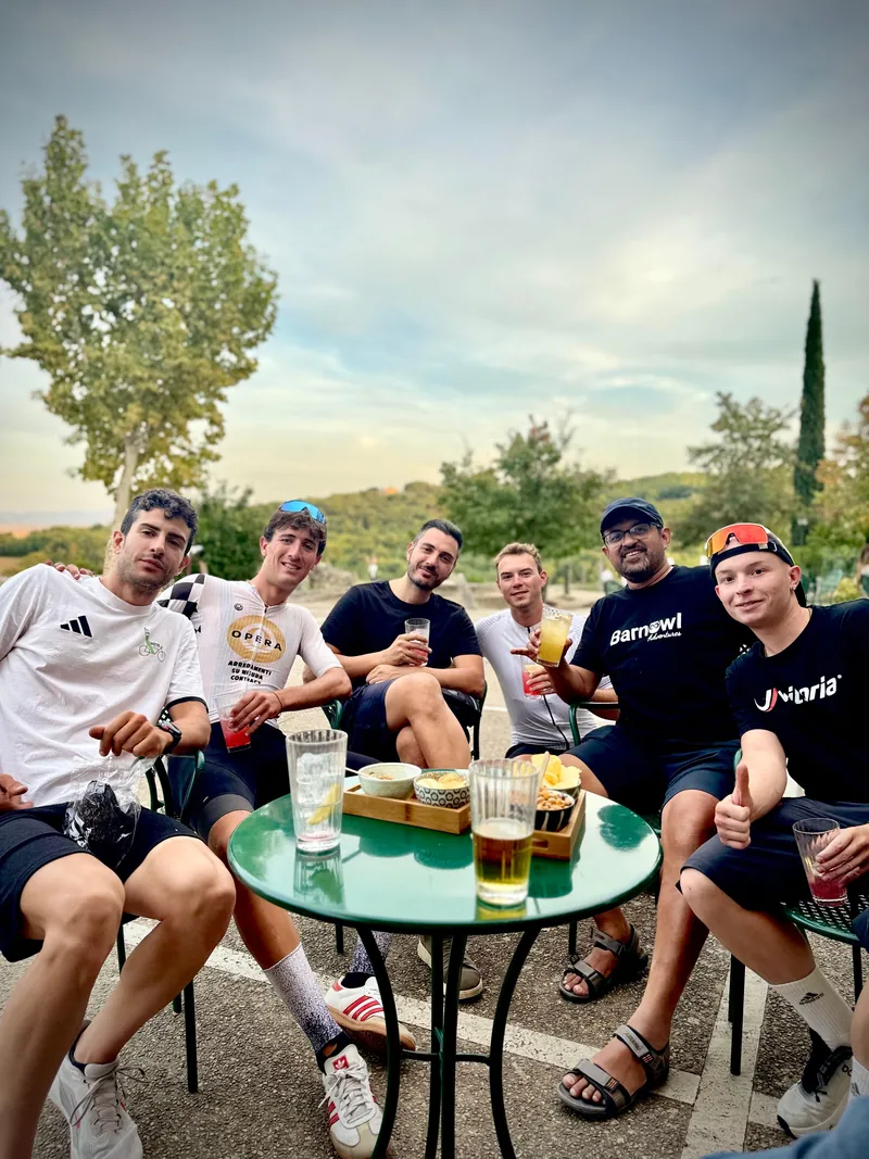 Riders gathered round a small table with drinks outdoors in the evening
