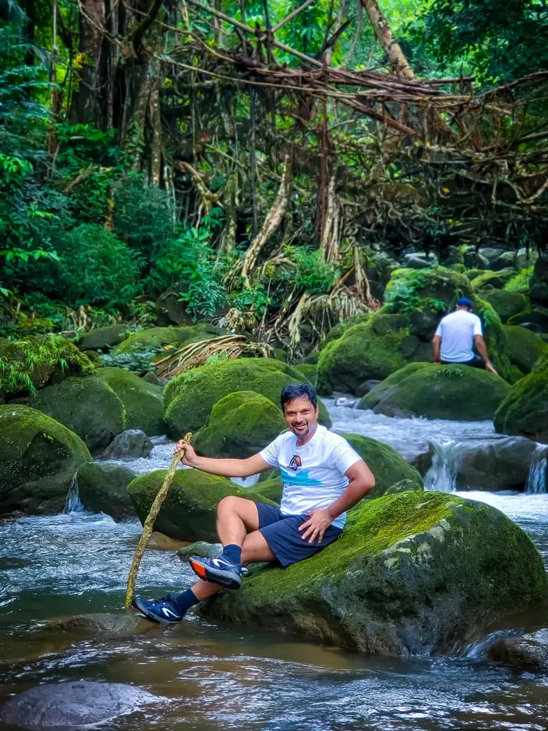 Sanjeet poses alongside a stream that flows beneath the root bridge we trekked on our rest day