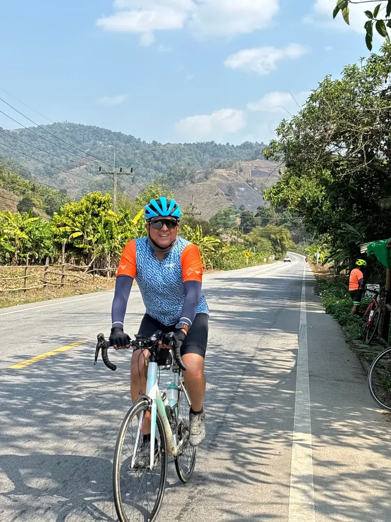 A rider on an empty two-lane road with green hills ahead